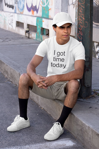 Person wearing a white t-shirt with 'I got time today' text, sitting on a sidewalk.